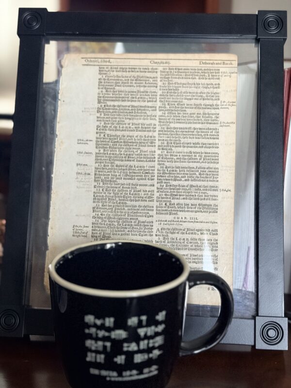 Teacup on my desk with passage from the Enuma Elish, promotional gift from Eisenbrauns. Behind, framed Page from the 1640 KJV.